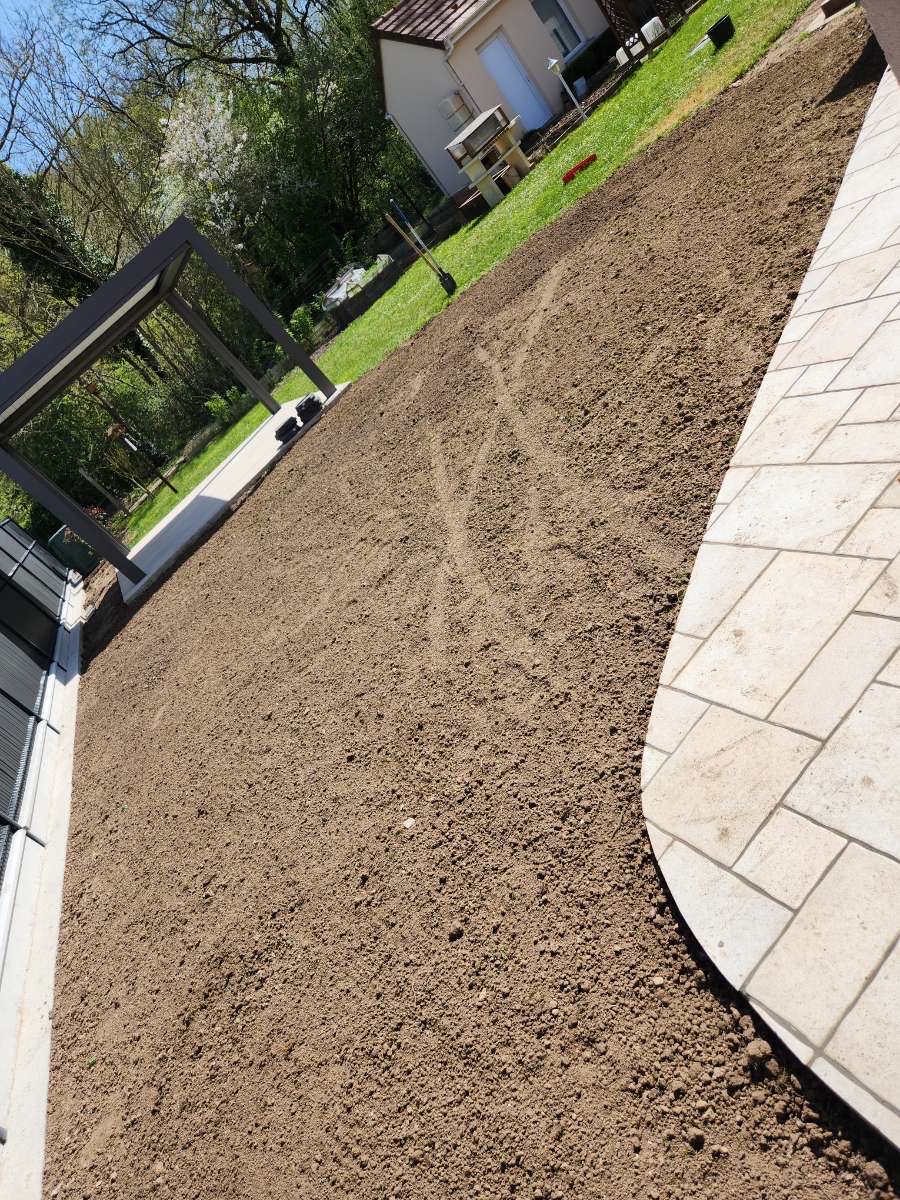 Sol préparé pour semis de gazon le long d'une terrasse pavée