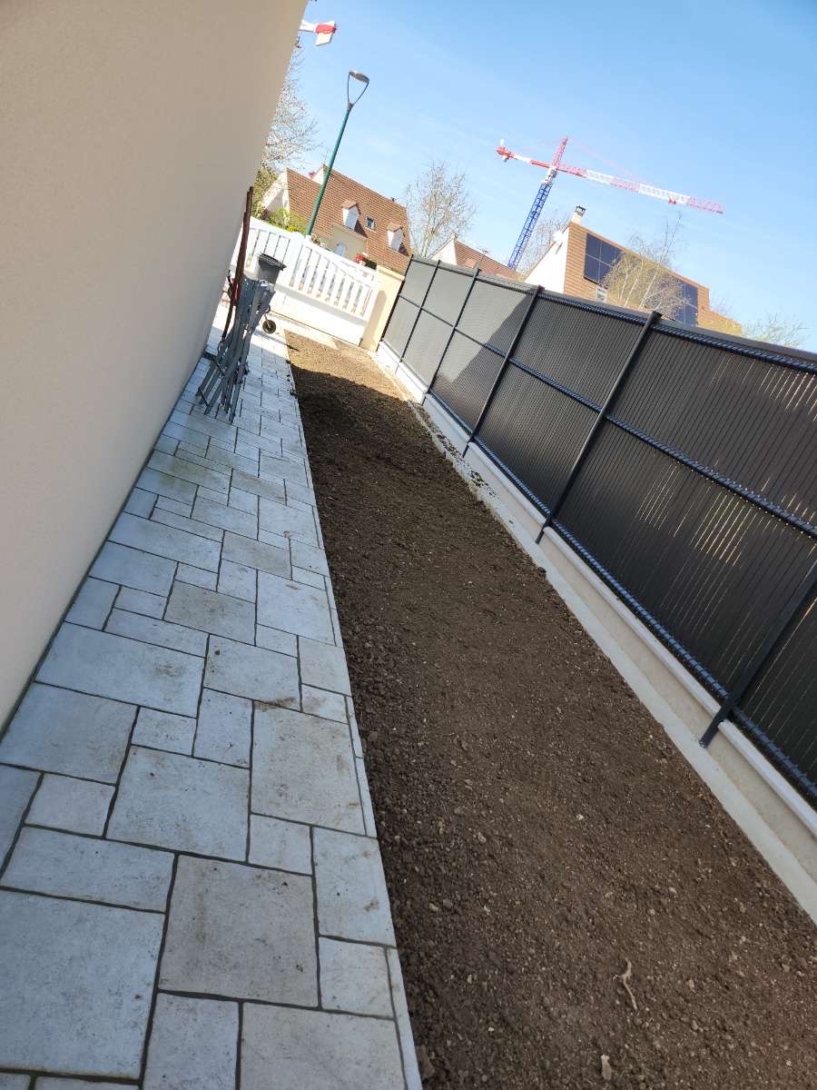 Allée pavée latérale entre maison et clôture à panneaux