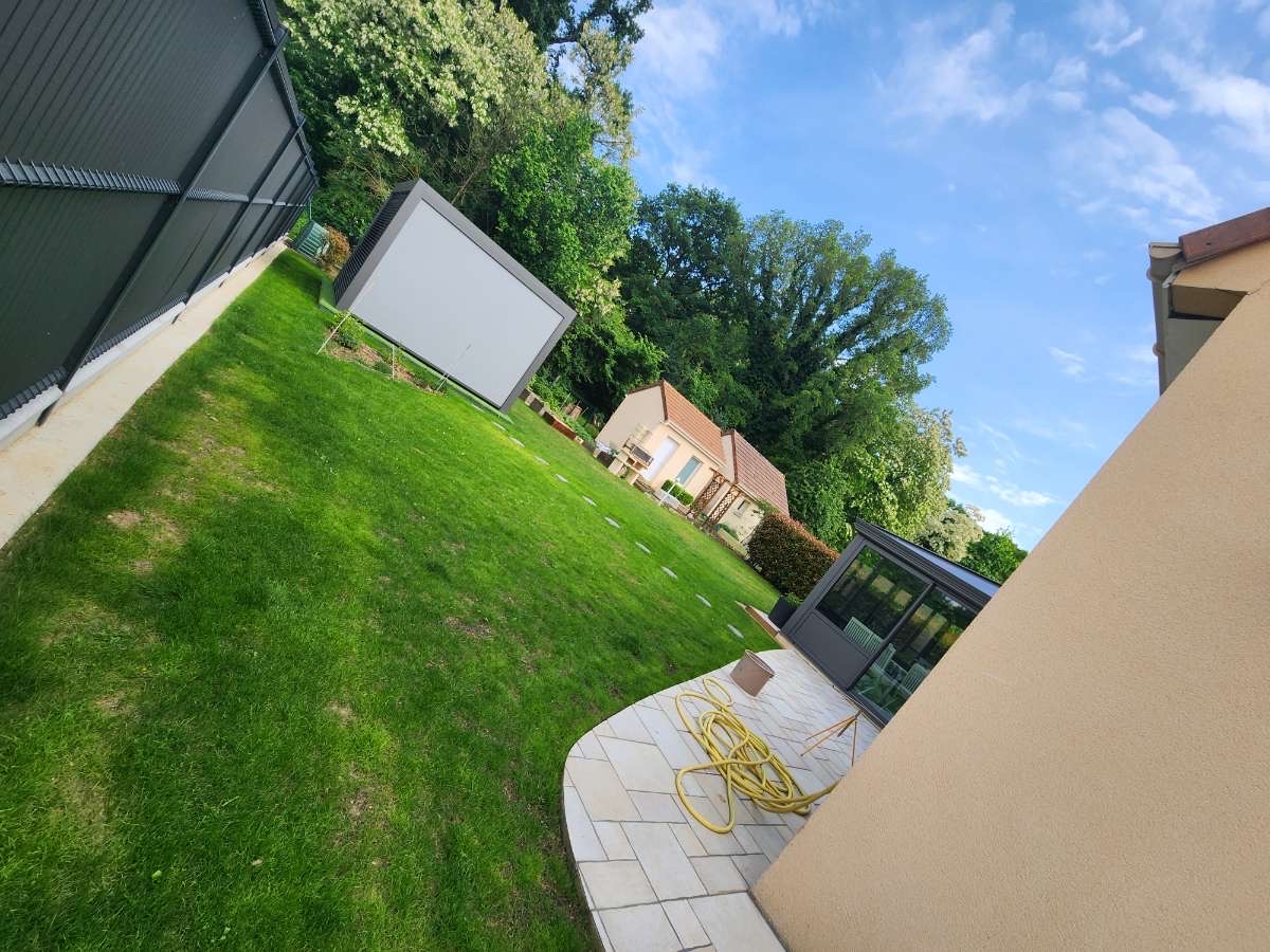Jardin aménagé avec pelouse verte et terrasse pavée en courbe